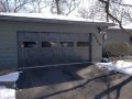 A modern charcoal grey garage door on a ranch style home.
